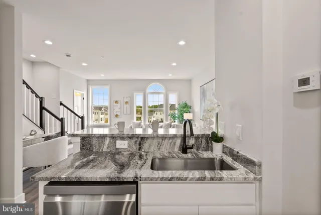 a kitchen with granite countertop a stove a sink dishwasher a refrigerator with white cabinets and wooden floor