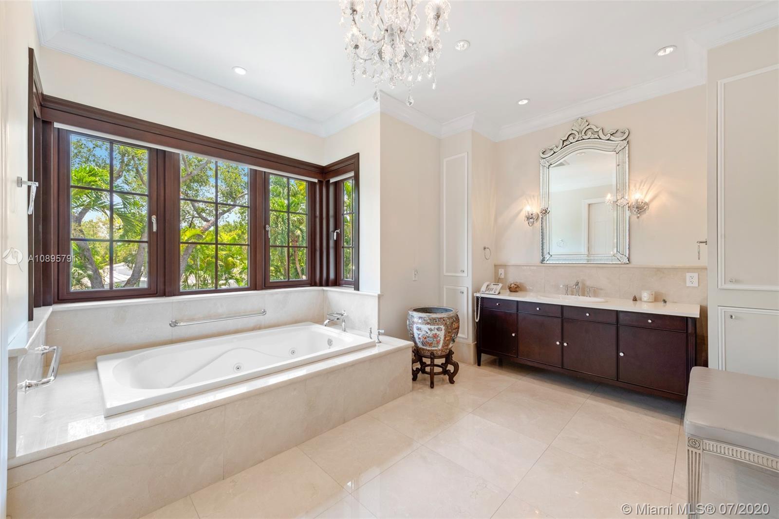 4800 Pine Drive Miami, FL 33143 - Photo 33 of 58 a spacious bathroom with a tub a double vanity sink a large mirror and a bathtub next to a window