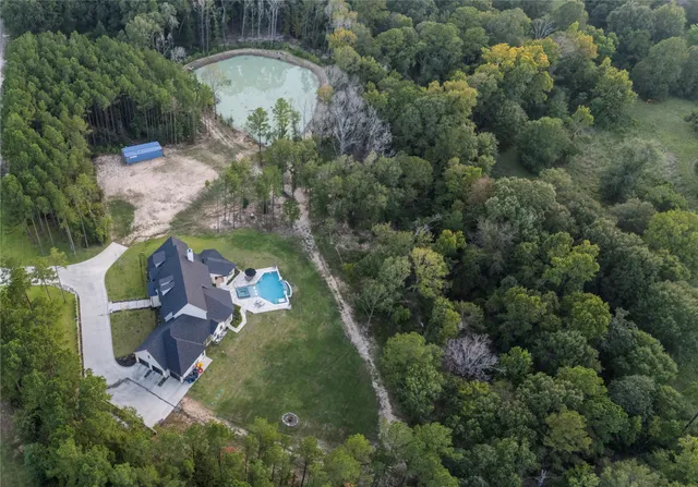 an aerial view of residential house with outdoor space and trees all around