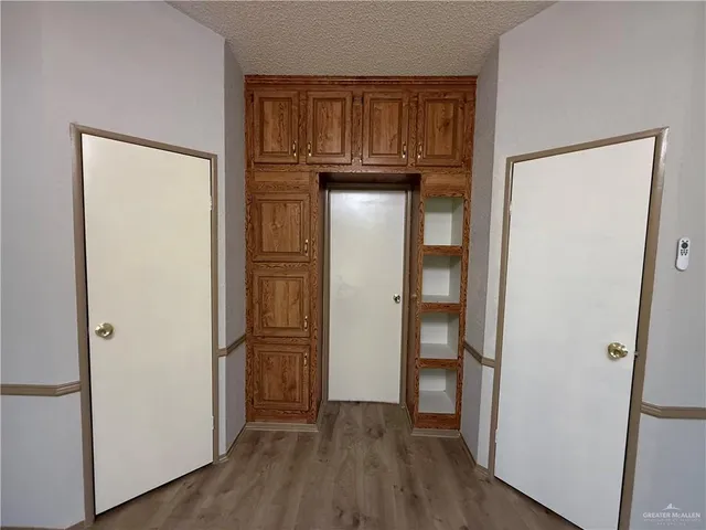 a view of an empty room with wooden floor and a cabinet