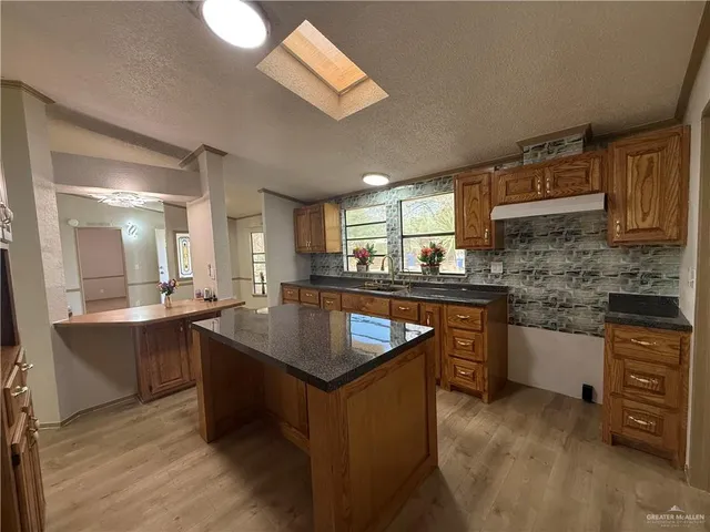 a kitchen with kitchen island granite countertop a sink stove and cabinets