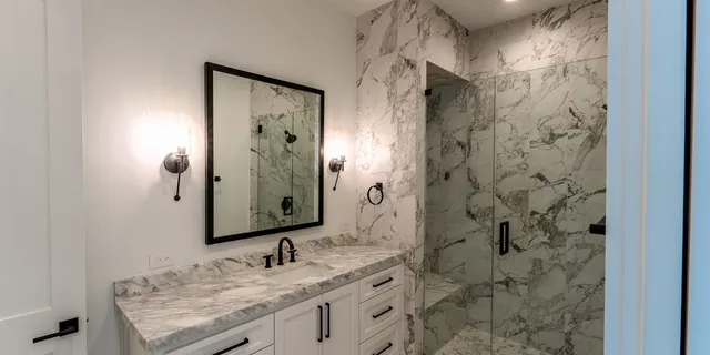a bathroom with a granite countertop sink a mirror and shower
