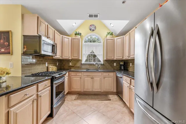 a kitchen with stainless steel appliances granite countertop a stove a sink and a refrigerator