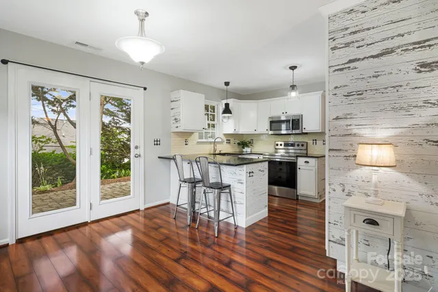 a open kitchen with granite countertop a stove a sink dishwasher a dining table and chairs with wooden floor