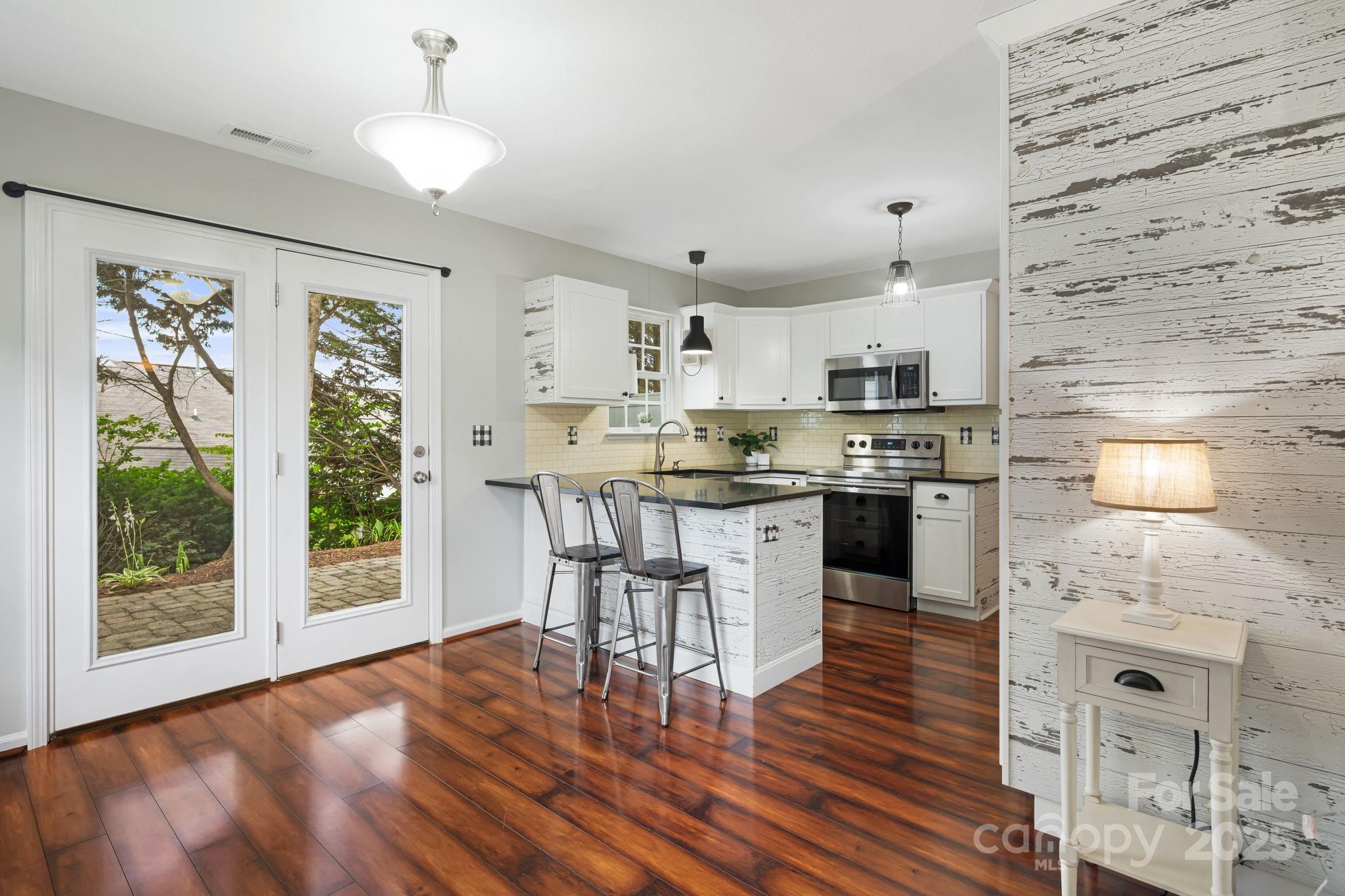 181 Farington Circle Fletcher, NC 28732 - Photo 6 of 33 a open kitchen with granite countertop a stove a sink dishwasher a dining table and chairs with wooden floor