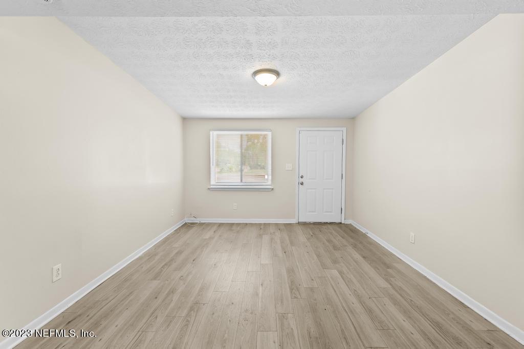 7256 Merrill Road Jacksonville, FL 32277 - Photo 11 of 36 an empty room with wooden floor and windows