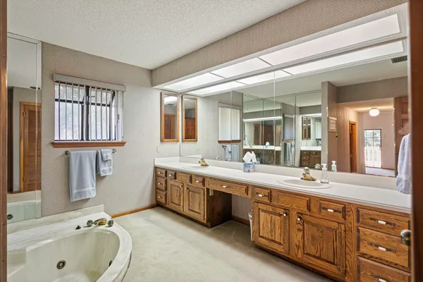 a spacious bathroom with a tub double sink and mirror