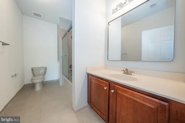 a bathroom with a granite countertop sink toilet and a mirror