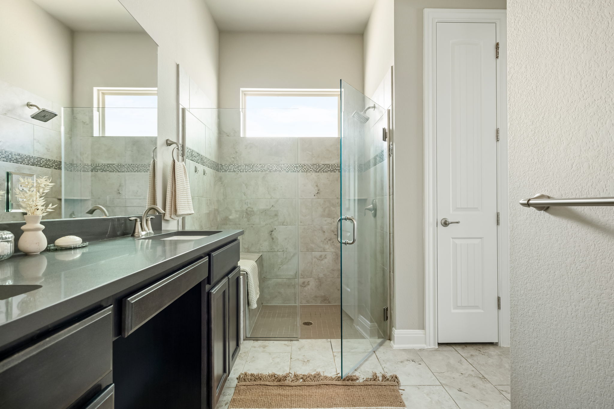 2516 Hopsack Mills Road Austin, TX 78748 - Photo 20 of 39 Bathroom featuring a glass-enclosed shower with a tiled bench, a double vanity with a dark countertop, and light-toned tile flooring