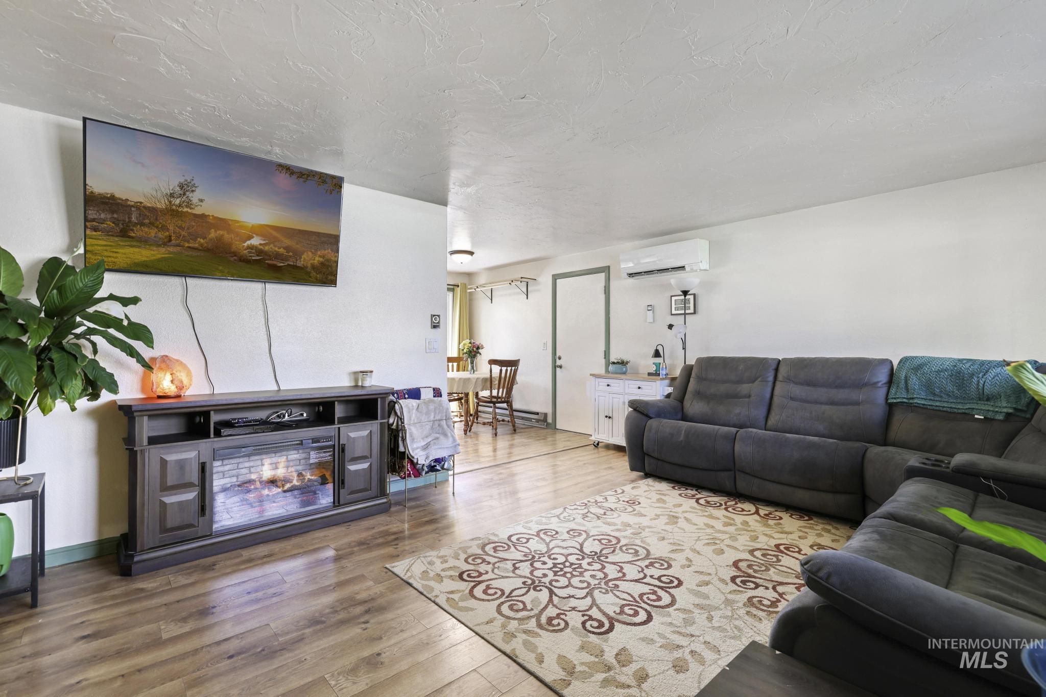 433 Ridgeway Drive Twin Falls, ID 83301 - Photo 3 of 18 Living room featuring wood finished floors, a glass covered fireplace, and a textured ceiling