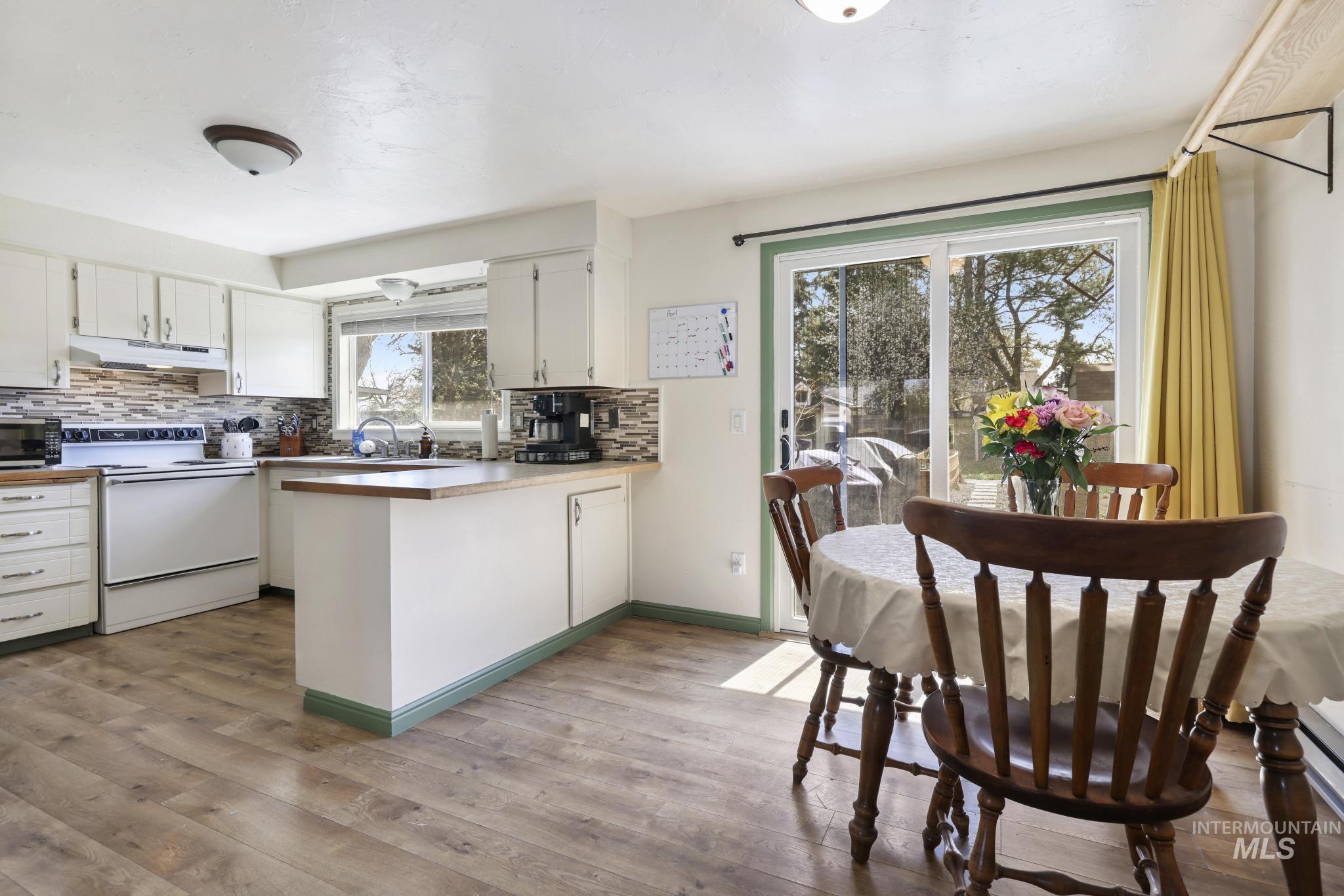 433 Ridgeway Drive Twin Falls, ID 83301 - Photo 5 of 18 Kitchen with white cabinets, electric stove, a peninsula, light wood-style floors, and decorative backsplash