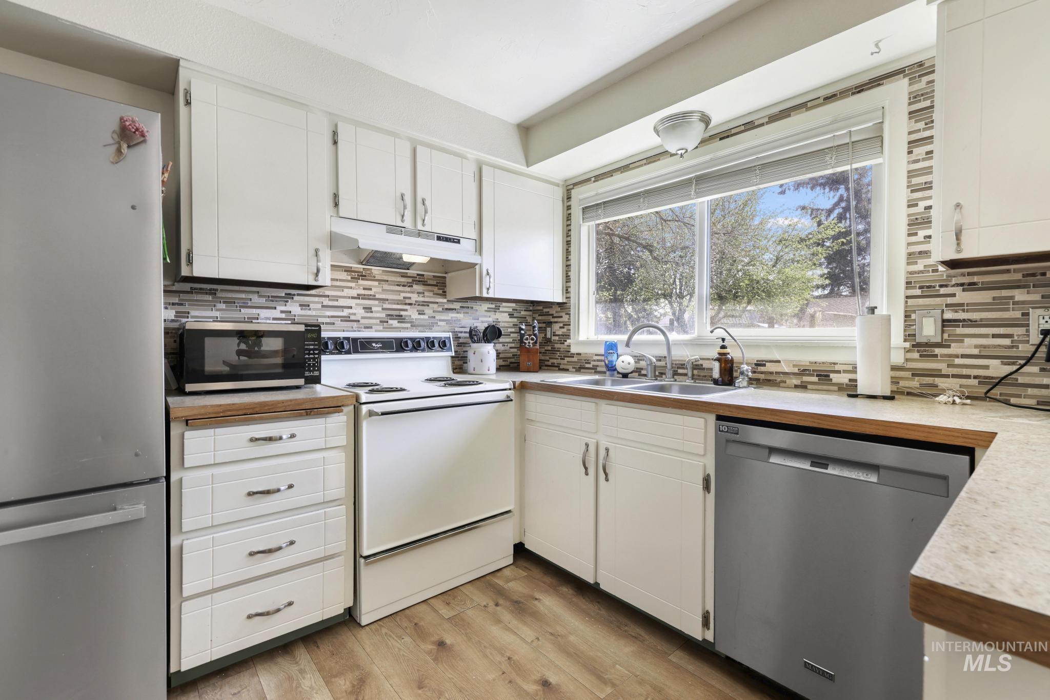 433 Ridgeway Drive Twin Falls, ID 83301 - Photo 6 of 18 Kitchen featuring stainless steel appliances, white cabinets, light countertops, and light wood-style floors
