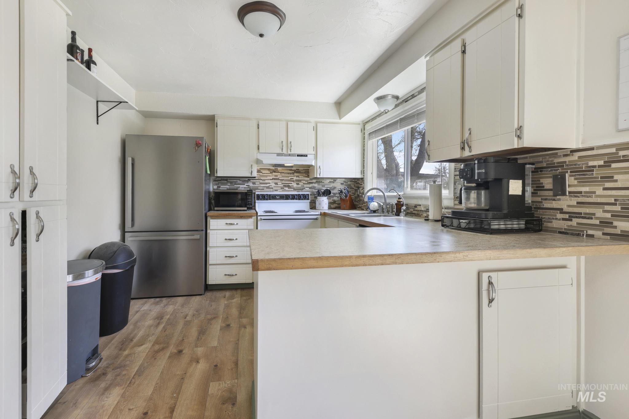 433 Ridgeway Drive Twin Falls, ID 83301 - Photo 7 of 18 Kitchen with light countertops, stainless steel appliances, white cabinets, a peninsula, and dark wood-type flooring