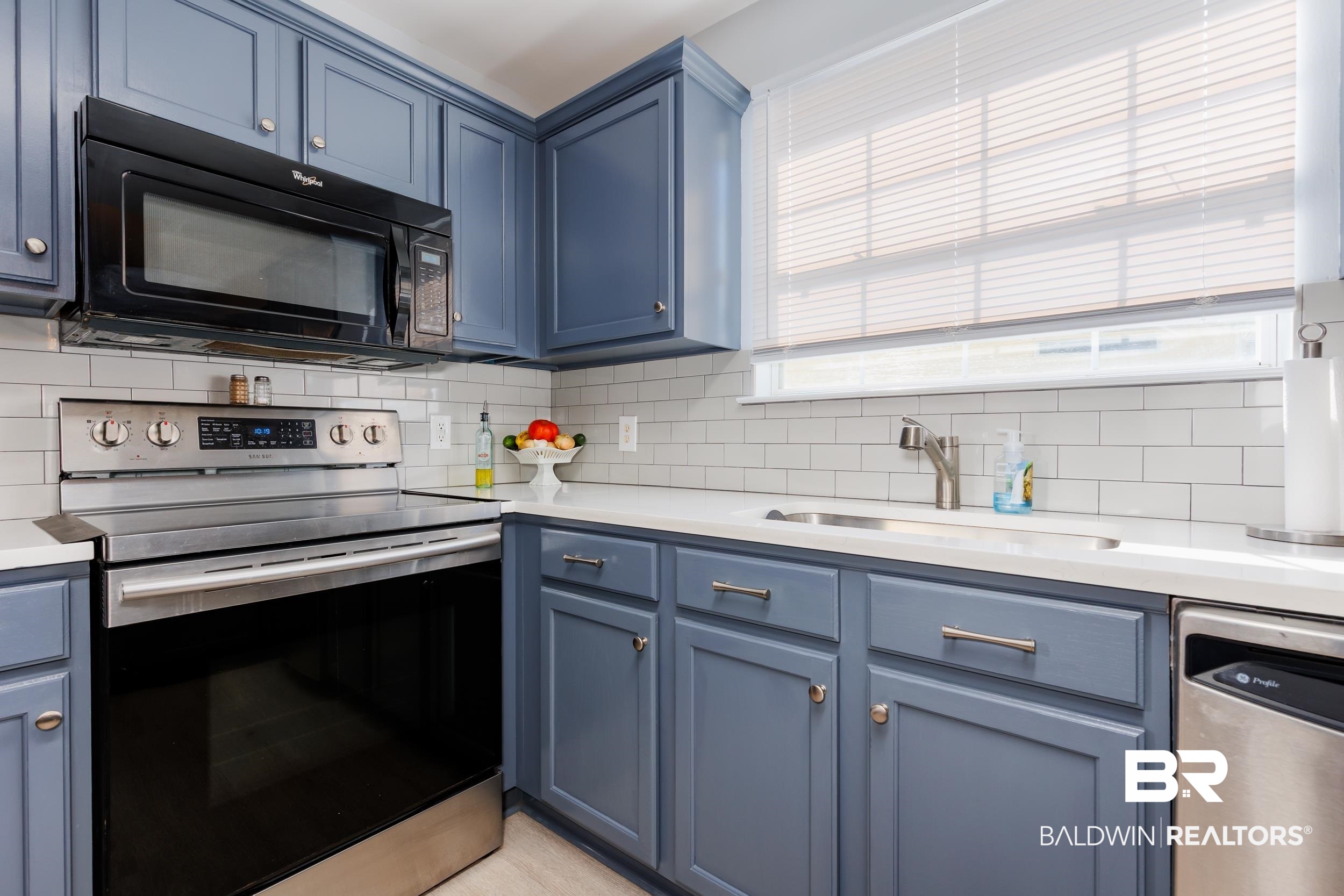 16227 Zenith Drive Loxley, AL 36551 - Photo 6 of 23 Kitchen with appliances with stainless steel finishes, blue cabinetry, tasteful backsplash, and light stone countertops