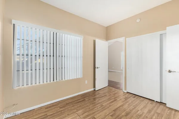 a view of an empty room with wooden floor and a window