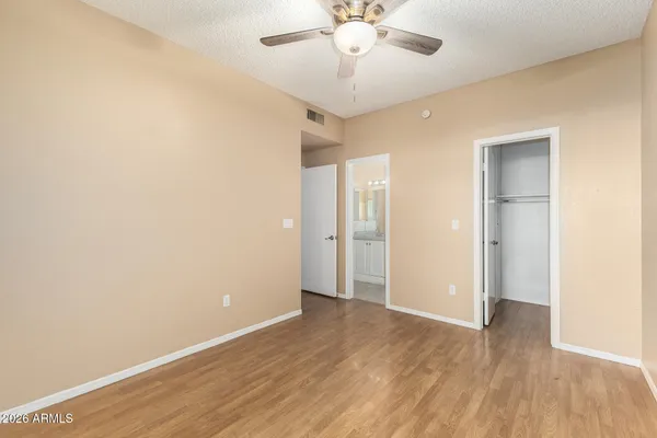 an empty room with wooden floor and ceiling fan