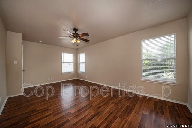 a view of an empty room with wooden floor and a window
