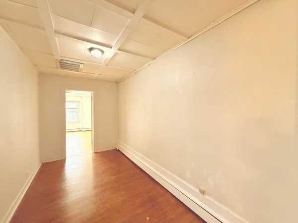 a view of empty room with wooden floor