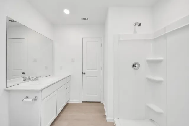 a bathroom with a double vanity sink a mirror and a shower