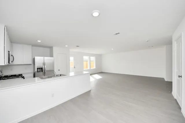 a view of large kitchen with a sink and a stove top oven