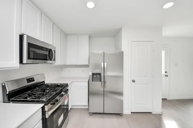 a kitchen with stainless steel appliances a refrigerator a stove top oven a sink and dishwasher