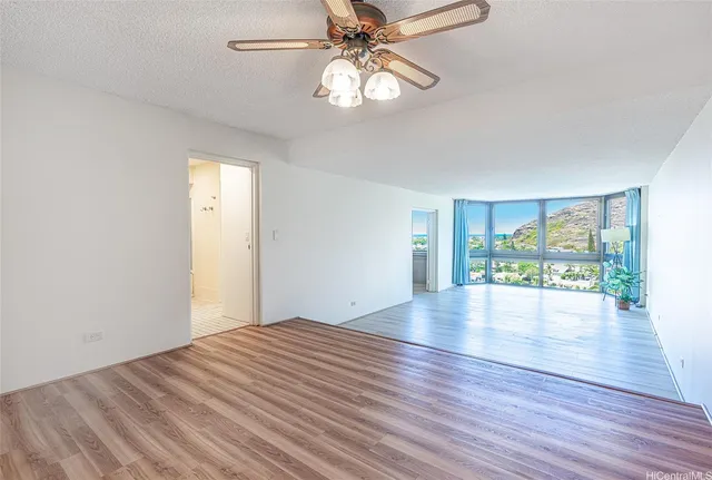a view of an empty room with window wooden floor and chandelier