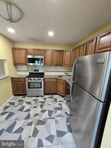 a kitchen with stainless steel appliances granite countertop a refrigerator a stove a sink a dining table and chairs