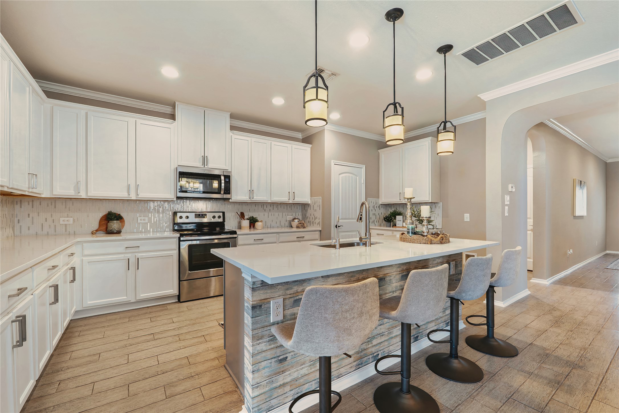 207 Telluride Drive Georgetown, TX 78626 - Photo 12 of 40 Kitchen featuring tasteful backsplash, arched walkways, stainless steel appliances, white cabinets, and a breakfast bar area