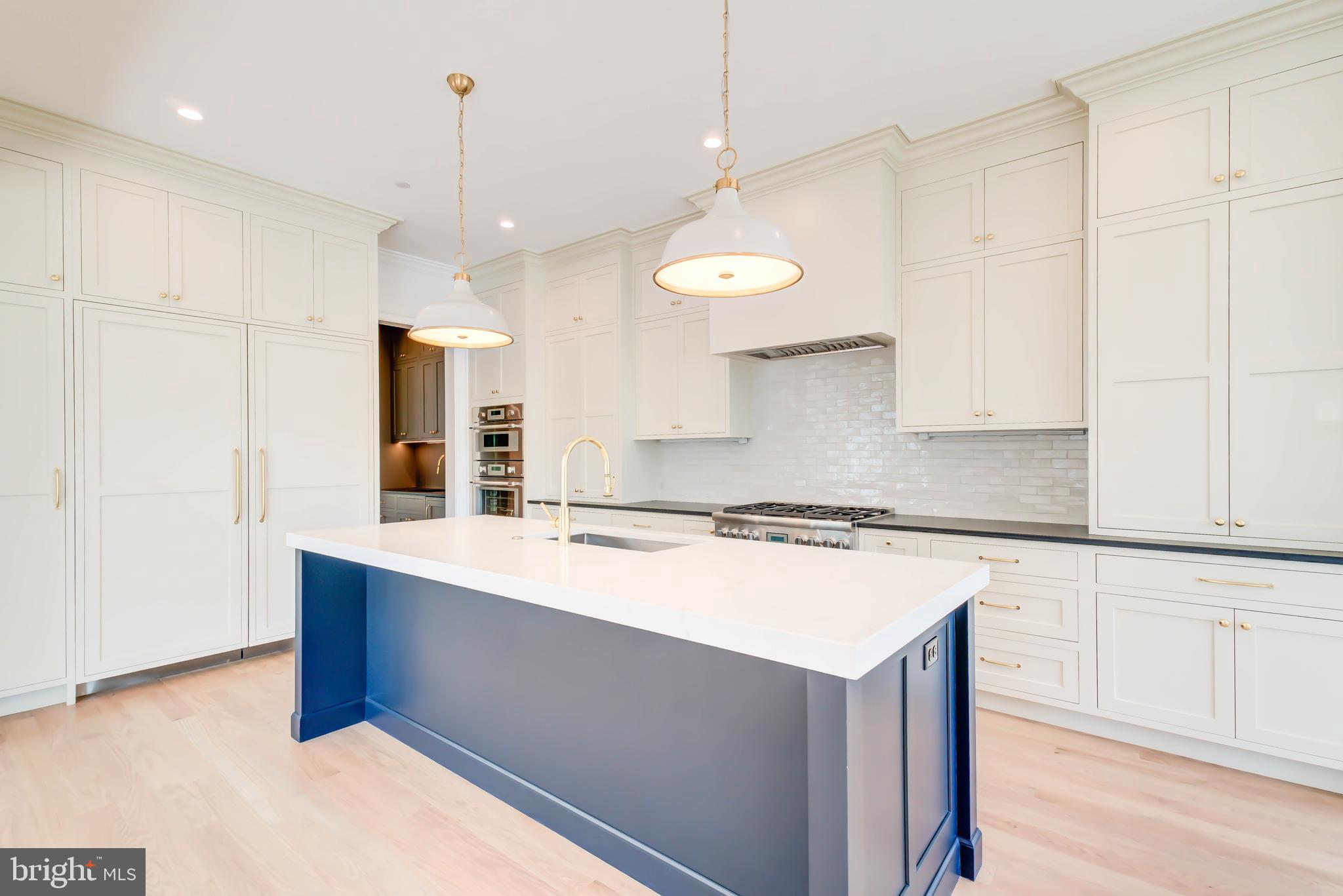 3118 Patterson Street Northwest Washington, DC 20015 - Photo 22 of 79 a kitchen with a stove a refrigerator a sink and white cabinets with wooden floor