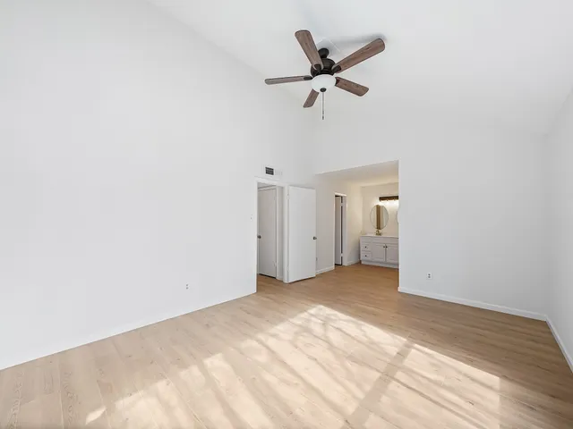 an empty room with a white wall and ceiling fan