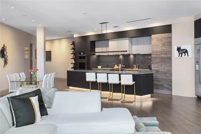 a living room with couches chairs and kitchen view with wooden floor