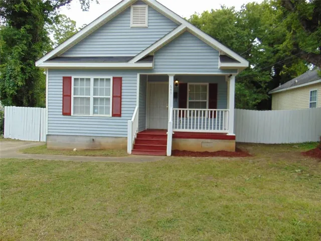 a view of a house with a small yard and wooden fence