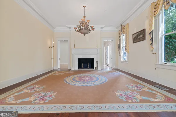 a view of an empty room with wooden floor fireplace and a window