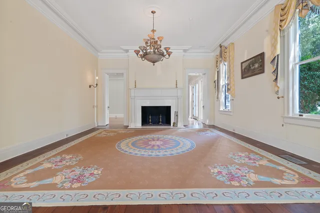 a view of an empty room with wooden floor fireplace and a window