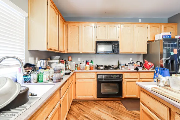 a open kitchen with stainless steel appliances granite countertop a refrigerator a sink dishwasher a stove and white countertops with wooden floor