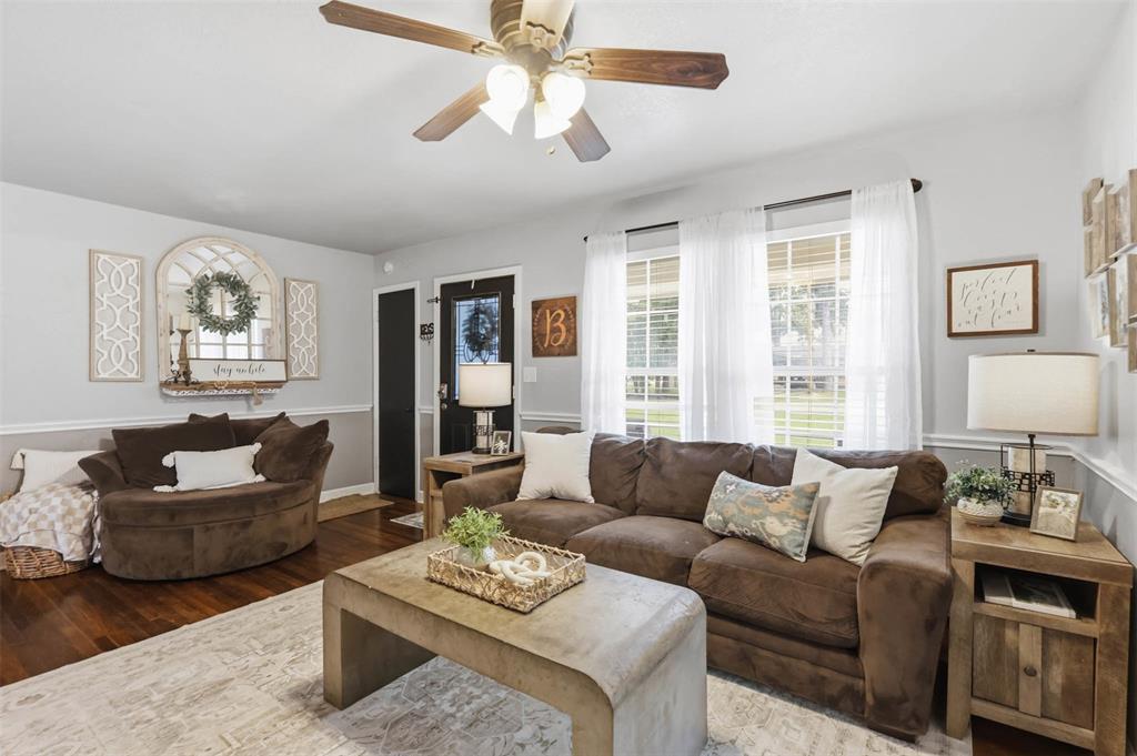308 West 1st Street Springtown, TX 76082 - Photo 10 of 39 Living area featuring wood-finish flooring, light gray walls with chair rail molding, and a ceiling fan with integrated lighting