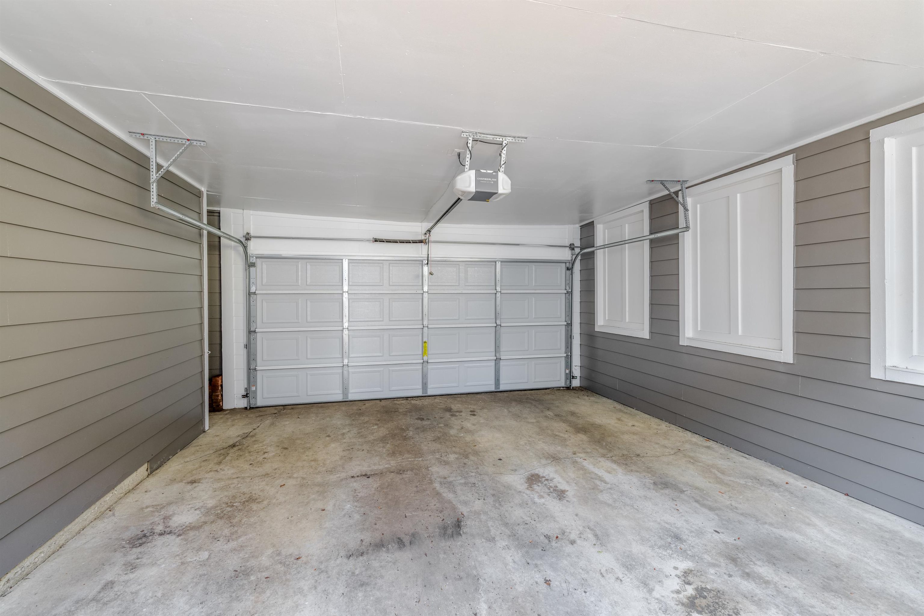 921 Harbor View Drive Memphis, TN 38103 - Photo 15 of 33 Garage with concrete flooring, automatic opener, white paneled garage door, grey horizontal siding, and multiple framed wall panels