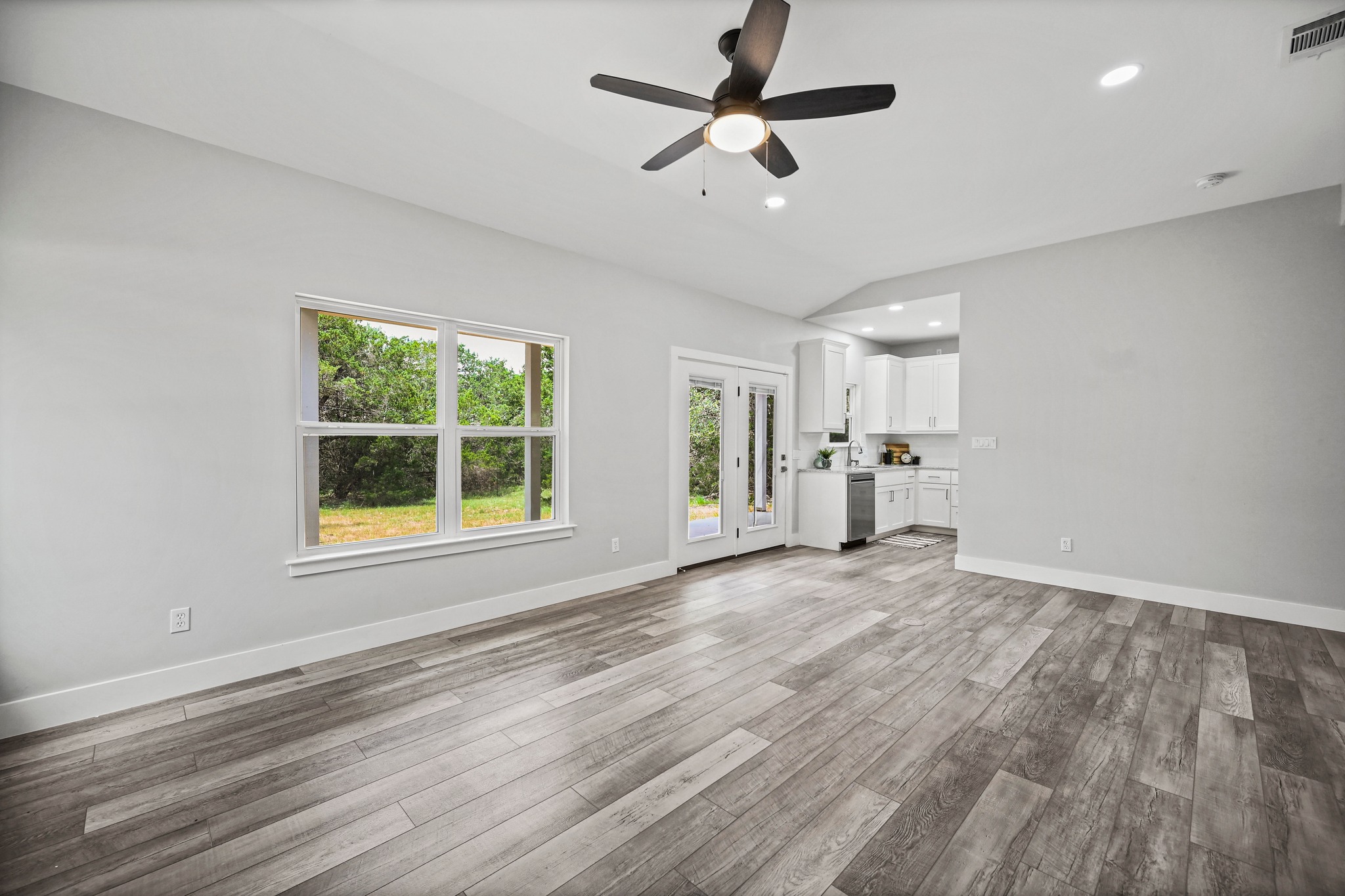 231 North Rainbow Ranch Road Wimberley, TX 78676 - Photo 11 of 40 A luminous living area seamlessly connects to the kitchen, offering serene backyard views through ample windows.