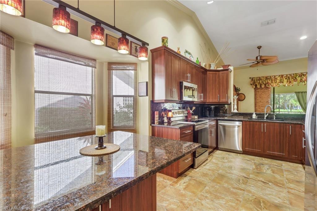 478 Countryside Drive Naples, FL 34104 - Photo 18 of 46 a kitchen with kitchen island granite countertop a stove a sink and a wooden cabinets