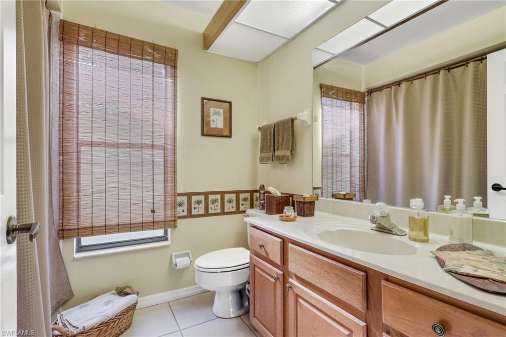 478 Countryside Drive Naples, FL 34104 - Photo 21 of 46 a bathroom with a granite countertop sink mirror vanity and toilet