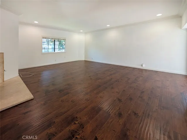 an empty room with wooden floor a fireplace and windows
