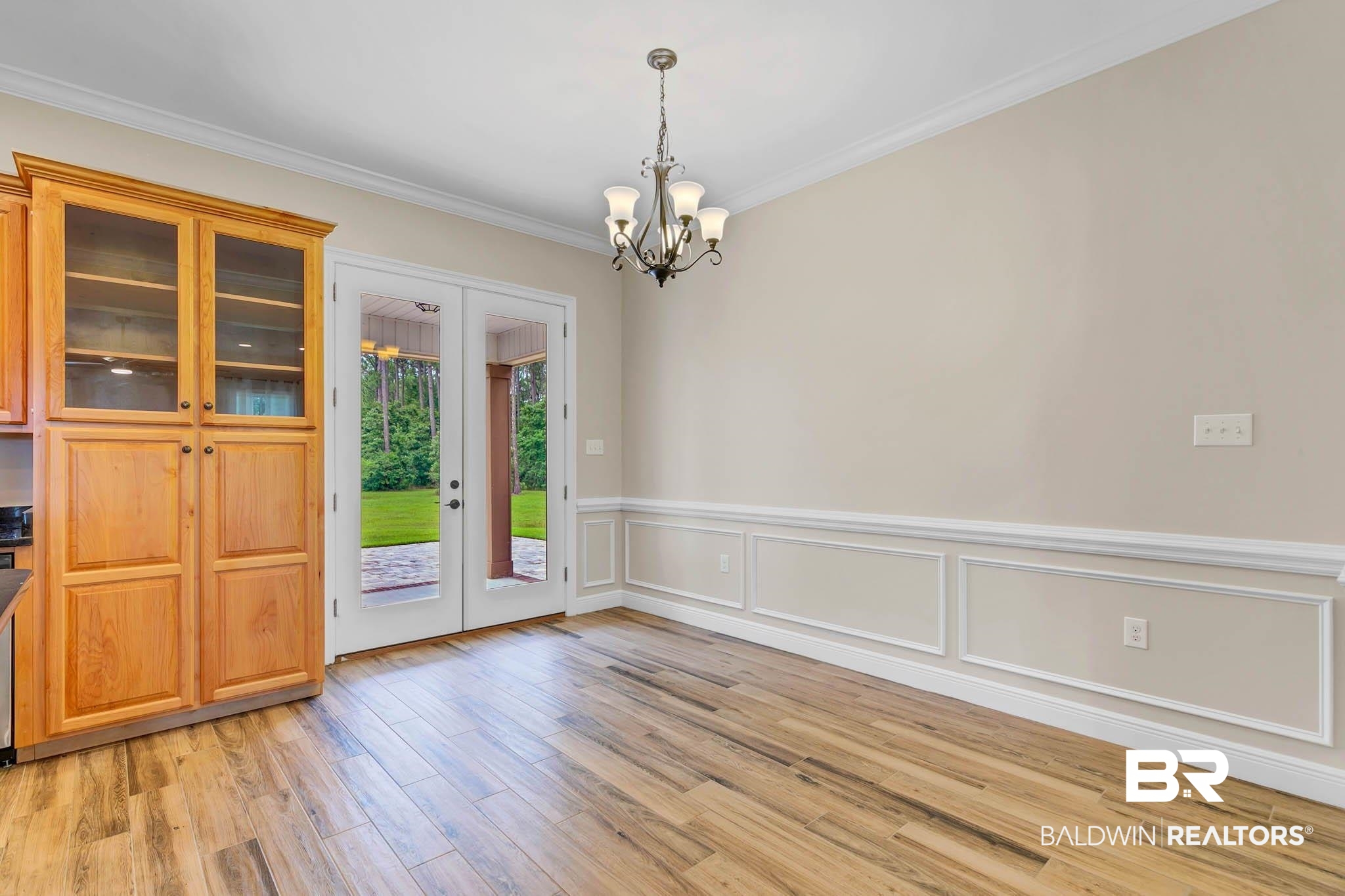 8145 Bay View Drive Foley, AL 36535 - Photo 14 of 81 Unfurnished dining area featuring a chandelier, french doors, light wood-type flooring, ornamental molding, and a wainscoted wall