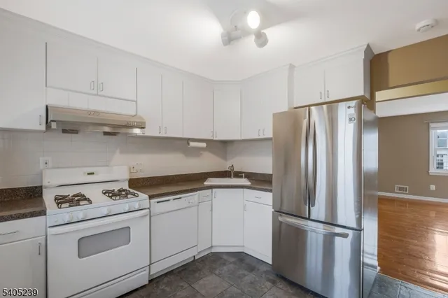 a kitchen with appliances a refrigerator and cabinets