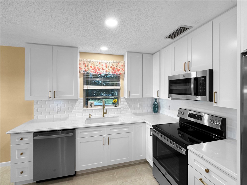 a kitchen with stainless steel appliances a sink dishwasher stove microwave and cabinets