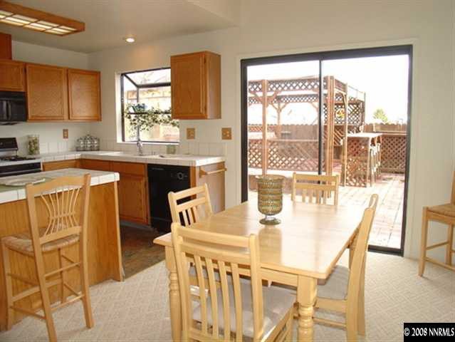 5877 Bankside Way Reno, NV 89523 - Photo 3 of 9 a kitchen with stainless steel appliances granite countertop a stove a refrigerator a dining table and chairs with wooden floor