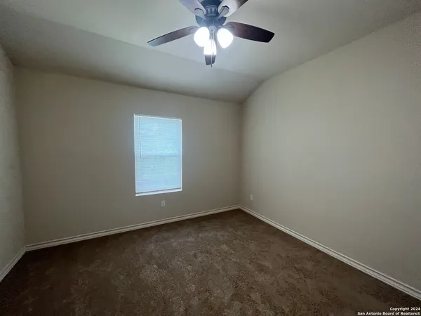 an empty room with a window and a fan