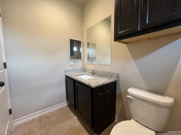 a bathroom with a granite countertop toilet sink and mirror