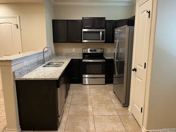 a kitchen with granite countertop a refrigerator and a sink