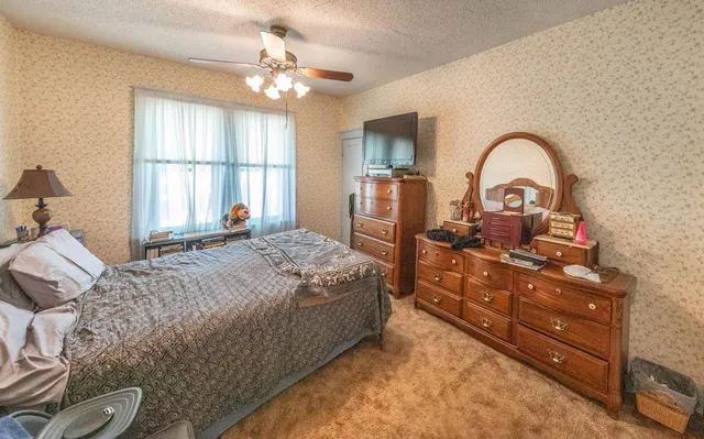 a bedroom with a bed and a large window with a chandelier