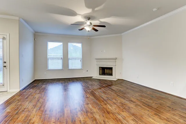 an empty room with wooden floor chandelier fan and windows